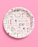Decorative plate with book-themed illustrations on a pink background