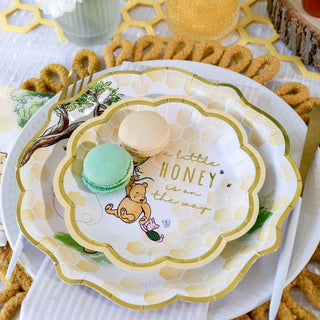 Decorative plate with Winnie the Pooh design and macarons on a table setting.