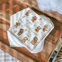 Stack of paper napkins with teddy bear design on a wooden surface