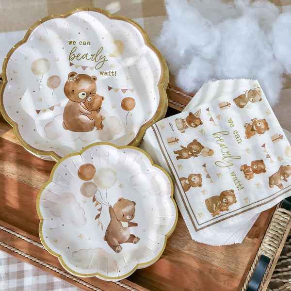 Set of paper plates and napkins with bear illustrations and text on a wooden surface.