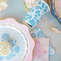 Table setting with floral-patterned plates, napkins, and cutlery on a light background.
