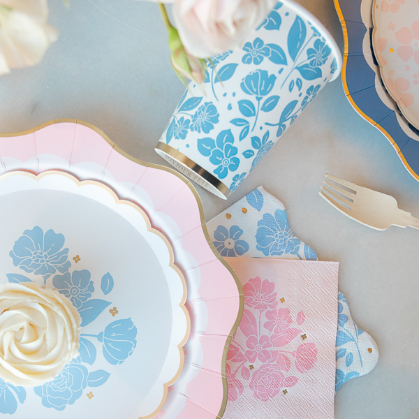 Table setting with floral-patterned plates, napkins, and cutlery on a light background.