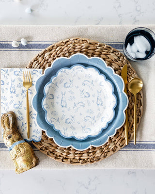 Easter table setting with blue decorative plate, gold bunny figurine, and silverware on a textured surface.