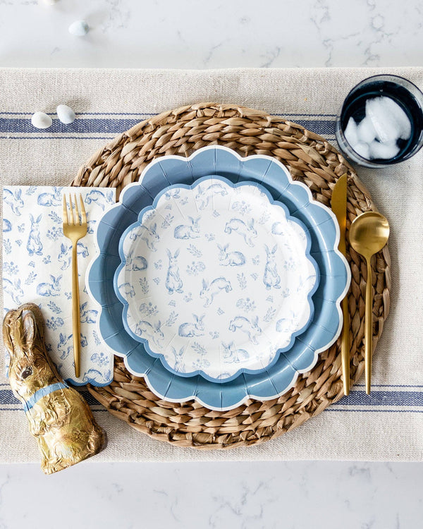 Easter table setting with blue decorative plate, gold bunny figurine, and silverware on a textured surface.