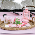 Pink lantern and cups on a woven tray in front of a pink car