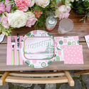 Table setting with a 'Bachelorette' themed plate, pink napkins, and floral decorations.