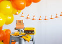 Construction-themed party decorations with balloons, cones, and signs on a white background