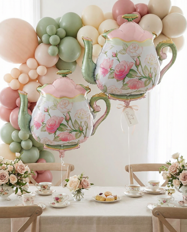 Decorative floral teapots with balloons and a table setting in the background