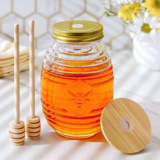 Jar of honey with wooden dipper and honeycomb lid on a light background