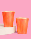 Two orange cups on a pink background