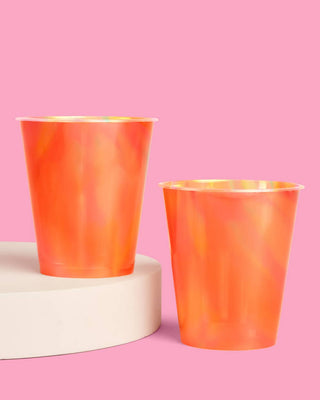 Two orange cups on a pink background