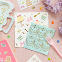 Decorative napkins with gold designs on a pink surface with stationery items.