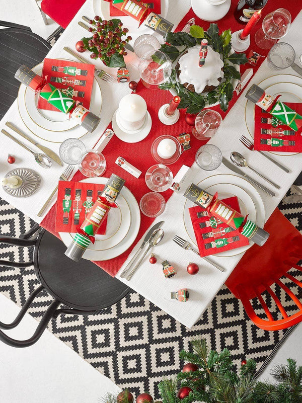 Christmas-themed table setting with red and white tablecloth, decorative items, and patterned rug.