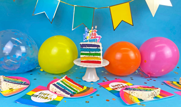 Birthday celebration with colorful cake, balloons, and decorations on a blue background