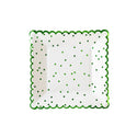 White plate with green scalloped edge and green polka dots on a white background