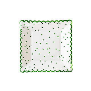 White plate with green scalloped edge and green polka dots on a white background