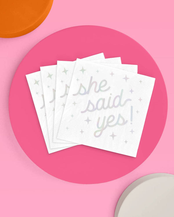 Stack of white napkins with 'she said yes!' text on a pink background
