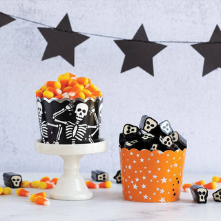 Halloween-themed cupcakes with skeleton design on a decorative background with stars.