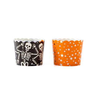 Two Halloween-themed cupcake liners, one with a skeleton design and the other with orange stars on a white background.