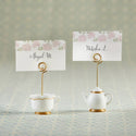 Tea cup and teapot-shaped photo holders with floral name cards on a textured surface.