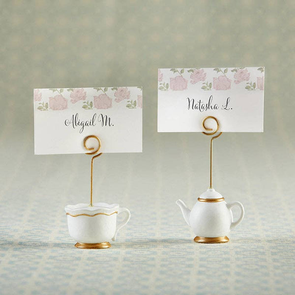 Tea cup and teapot-shaped photo holders with floral name cards on a textured surface.