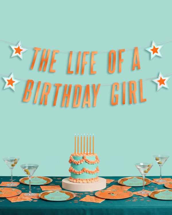 Birthday-themed table setting with cake and 'The Life of a Birthday Girl' text on a teal background