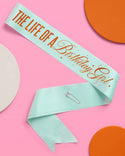 Light blue sash with 'The Life of a Birthday Girl' text on a pink background