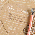 Heart-shaped 'Advice & Wishes' card for the new Mr. and Mrs. with a pen on a woven surface.