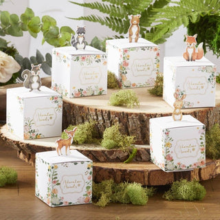 Decorative boxes with animal figurines on a wooden display with greenery