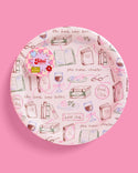 Round pink plate with book-themed illustrations on a pink background