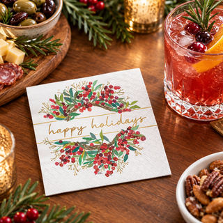 Happy Holidays Wreath cocktail napkin beside a holiday drink